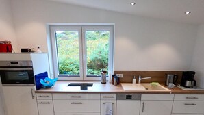 Una cucina moderna con un lavello doppio, forno integrato e una finestra vista sul verde.