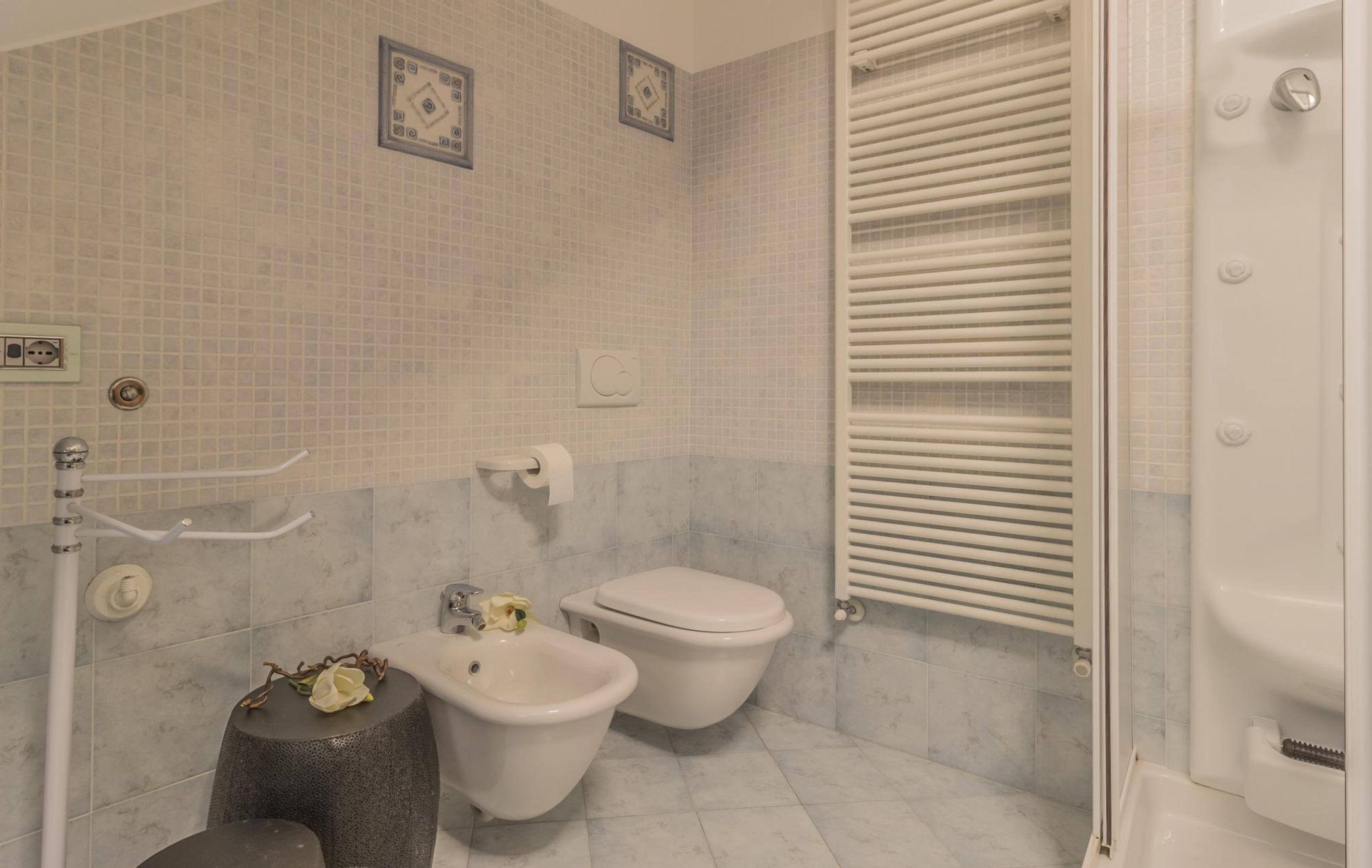 A bathroom with a bidet, toilet, and a towel rack.