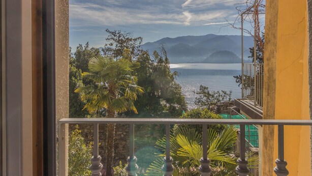 A balcony with a view of a lake, mountains, and trees. - Casa Magnolia Varenna (Varenna)