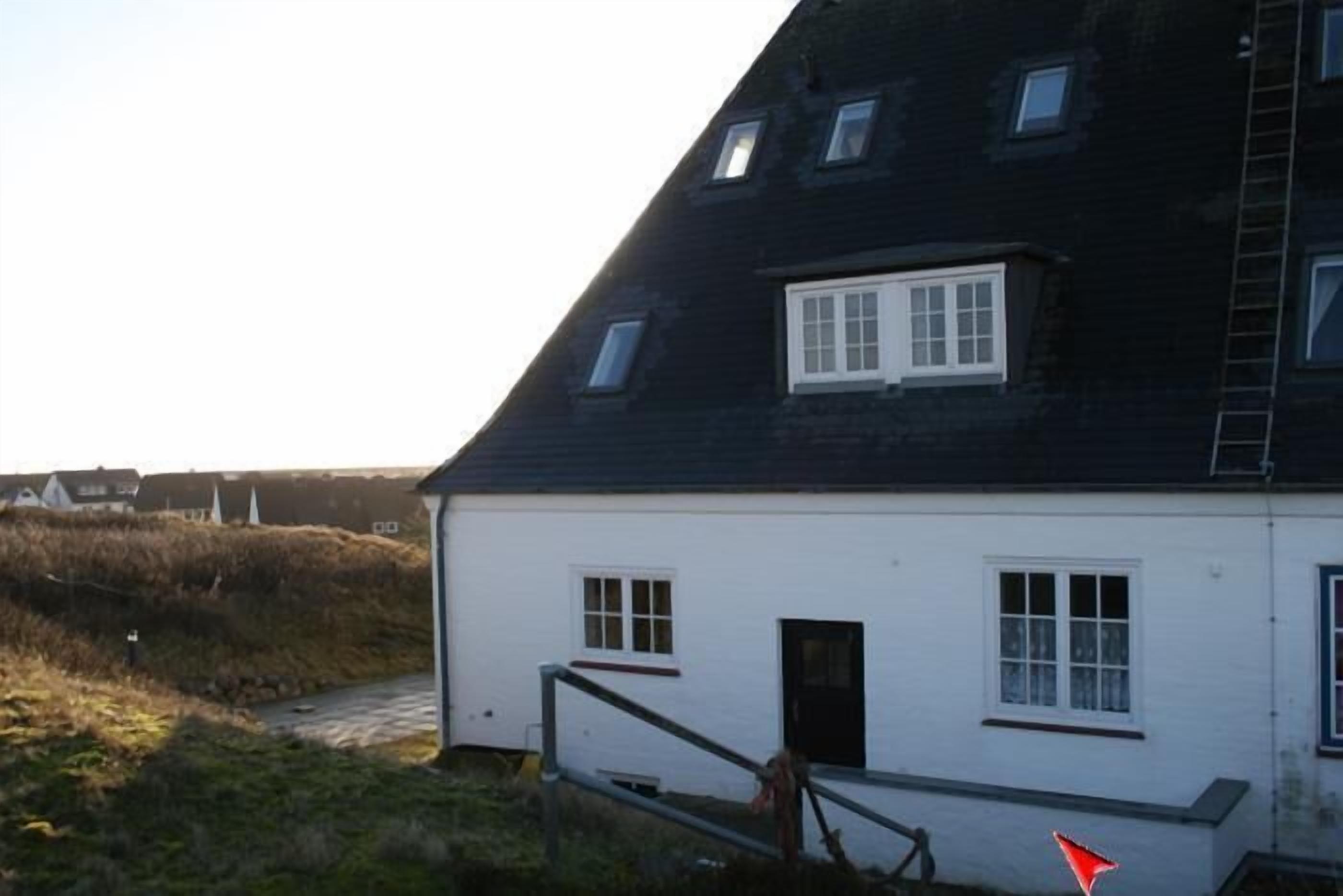 A white building with a black roof, multiple windows, and a visible door.