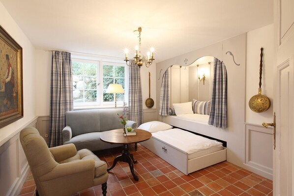 Un dormitorio con cama, sofá, mesa y ventana con cortinas.