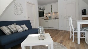 A compact living space with a sofa, a coffee table, and a dining area with chairs. - Top renovated apartment ideal for 3 persons (Hörnum auf Sylt)