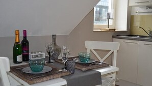 Comedor con una mesa dispuesta para dos personas, botellas de vino, copas y un tazón.