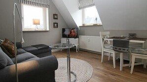 Un loft moderno con comedor, sofá, televisor y escalera.