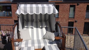 Una terraza de madera con un toldo a rayas y una zona de estar con cojines.