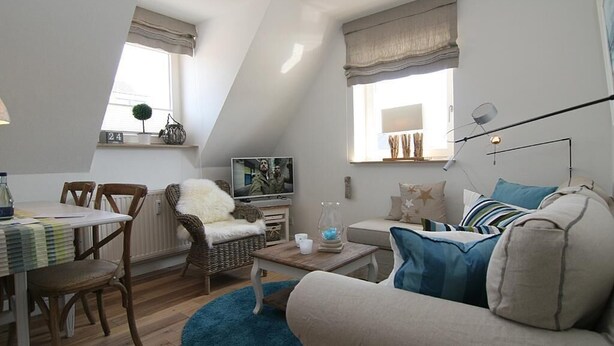 Una sala de estar estilo loft acogedora, con comedor, un ventanal con cortinas, televisor y una lámpara moderna.
