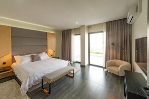 Habitación de hotel moderna con una cama grande, un banco, un escritorio, una silla y un televisor.