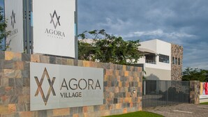 Um edifício moderno com fachada de pedra e uma placa com o nome 'Agora Village'.