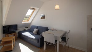 Uma sala de estar moderna com sofá, televisão, mesa e um claraboia.