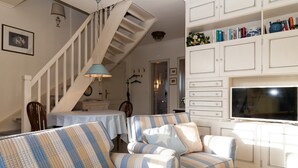 Ein Wohnzimmer mit Sofa, Fernseher und einer Treppe.