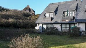 Ein Haus mit geneigtem Dach, einem sichtbaren Dachboden und einem großen Fenster.