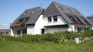 A modern two-story house with a sloped roof, large windows, and a well-maintained garden.