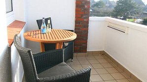 Uma pequena varanda com uma mesa de madeira redonda e duas cadeiras de vime.