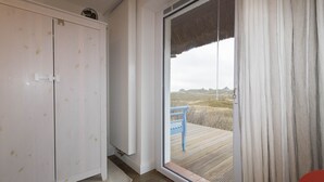 Ein Zimmer mit einem weißen Kleiderschrank und einer Schiebetür zu einem Außenbereich mit einem blauen Stuhl.