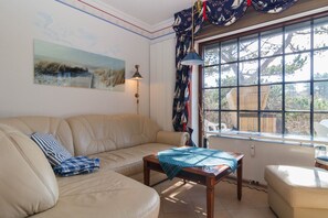 A living room with a beige sofa, a wooden coffee table, and a window with curtains.