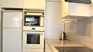 Une cuisine compacte dotée d’un four à micro-ondes, d’un four et d’une plaque de cuisson intégrés.
