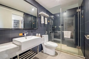 Uma casa de banho moderna com um espelho grande, uma sanita branca, uma casa de wc e um chuveiro com divisória de vidro.