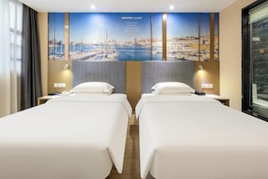 Quarto de hotel com duas camas, uma janela grande e um mural com vista para a cidade na parede.