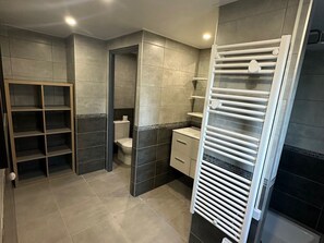 A bathroom with a toilet, a sink, a mirror, and a towel rack.