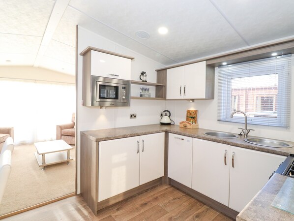 Cocina compacta con microondas, lavabo y armarios de madera.