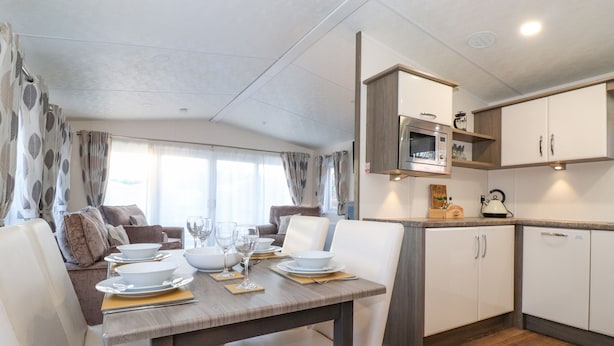 A modern RV kitchen with a microwave, sink, and cabinets. - Draco (Morpeth)