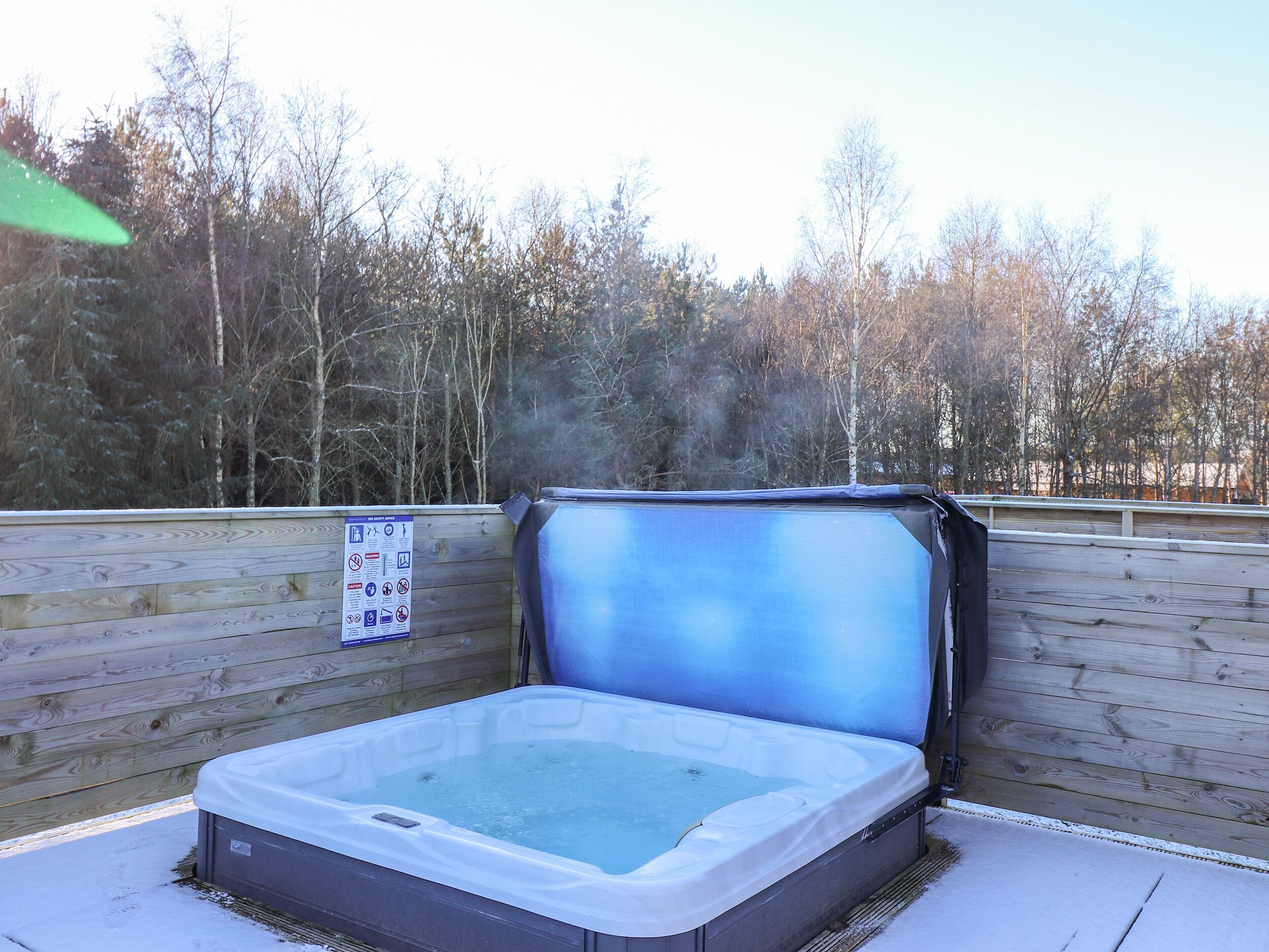 A hot tub with a wooden deck and a signboard.