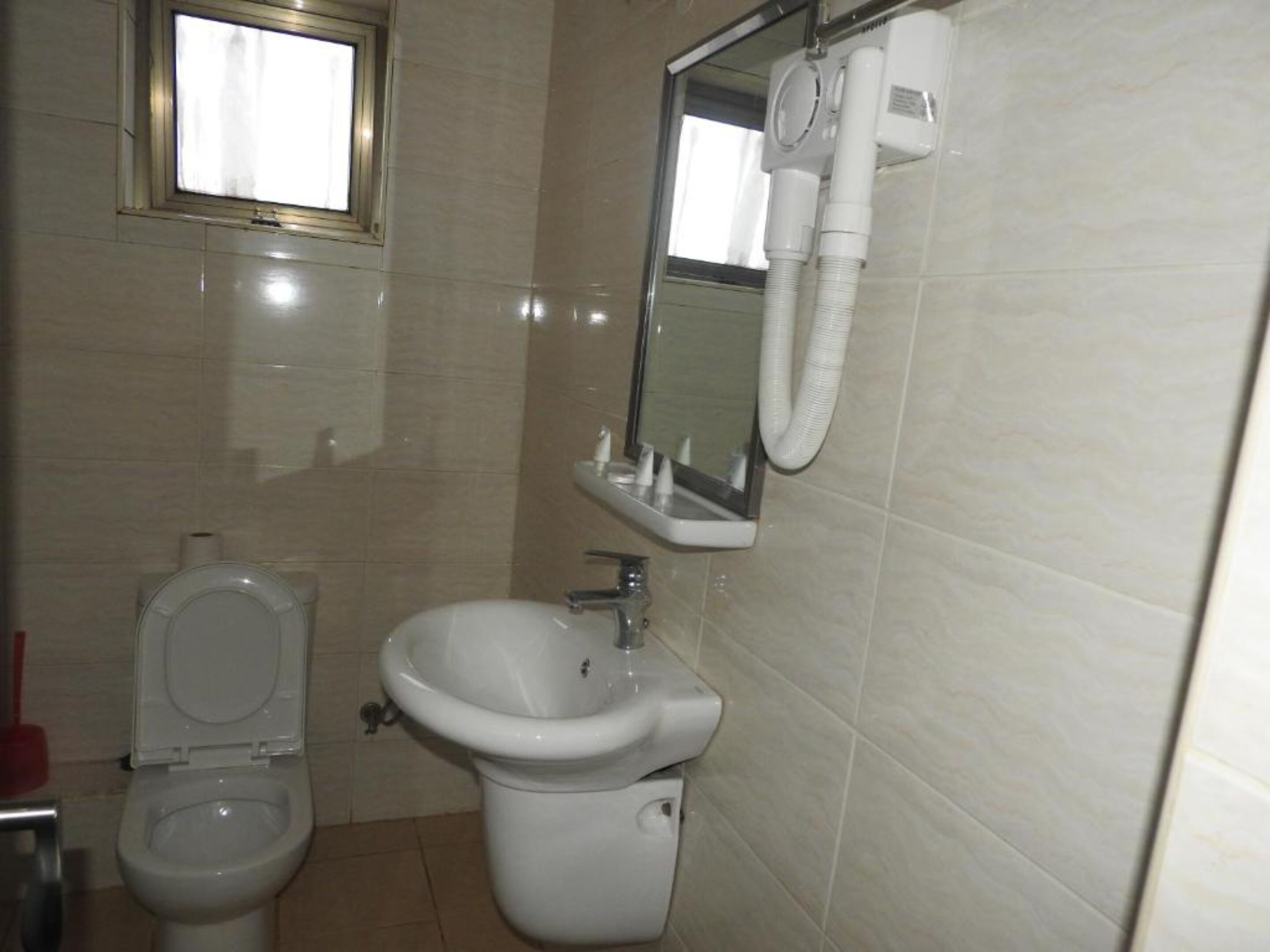 Et badeværelse med toilet, vask og spejl.