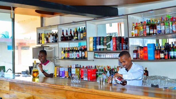 A bar area with shelves stocked with various liquor bottles and glasses. - Omega Gardens Hotel (Nanyuki)