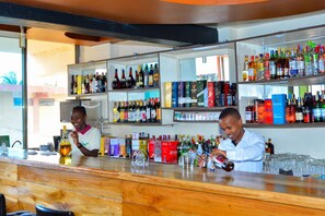 A bar area with shelves stocked with various liquor bottles and glasses. - Omega Gardens Hotel (Nanyuki)