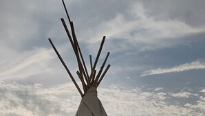 A large, conical structure with painted designs, set in a desert landscape.