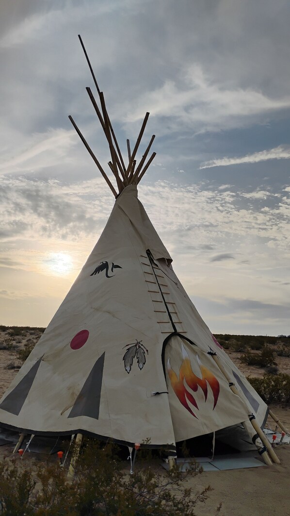 A large, conical structure with painted designs, set in a desert landscape.