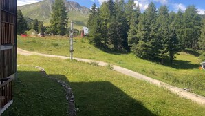 A grassy area with a path, a metal structure, and a mountain in the background. - Cozy studio at the foot of the slopes in Plagne Village (Plagne Villages)