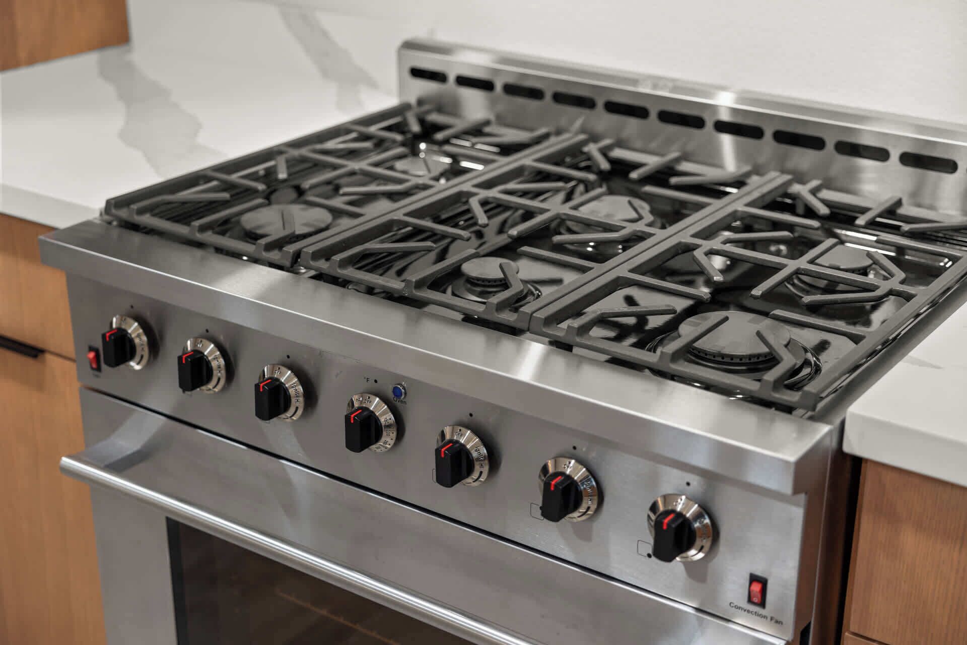 A stainless steel stove with four burners and a convection fan.