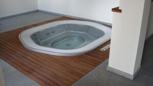 Ein Whirlpool mit Holzterrasse, integriertem Sitzbereich und kleiner Bedieneinheit.
