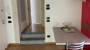 Ein modernes Interieur mit Holzboden, einem Esstisch mit roten Stühlen und einer Treppe, die in einen anderen Raum führt.