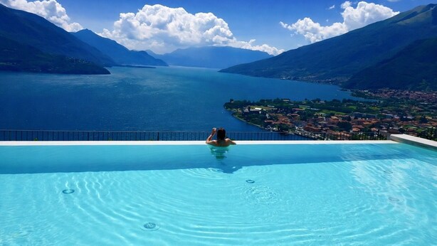 Ein Pool mit einer Person, mit Blick auf einen See und Berge.
