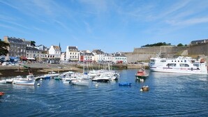 Ein Hafen mit Booten, einer Burg und Gebäuden entlang der Küste.
