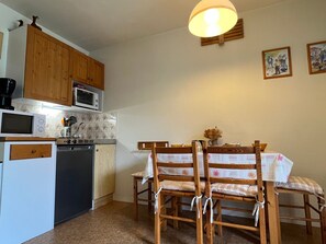 Eine kompakte Küche mit Holzausstattung, einer Mikrowelle, einem Herd und einem Essbereich mit Tisch und Stühlen.