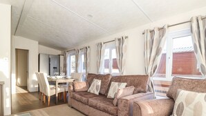 Una sala acogedora con un conjunto de sofás, una mesa de comedor y un ventanal con cortinas.