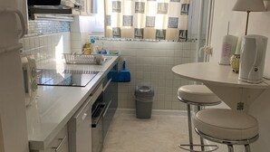 A modern kitchen with white cabinets, a stainless steel sink, and a small round table with two bar stools.