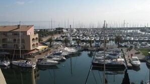 A marina with numerous boats docked, a building with a balcony, and a clear sky.