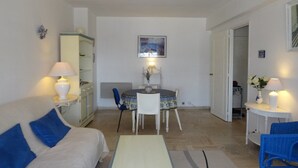 A living room with a sofa, a table, a chair, a cabinet, and a dining table with chairs.