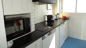 A compact kitchen with white cabinets, a black microwave, a toaster, and a dishwasher. - Hyères Port T2 with Air Conditioning and Wifi, Sea View (Hyères)