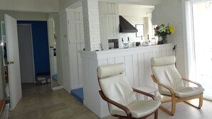 A modern kitchen with white cabinetry and a black range hood. There are two white leather chairs in front of the kitchen. - Hyères Port T2 with Air Conditioning and Wifi, Sea View (Hyères)