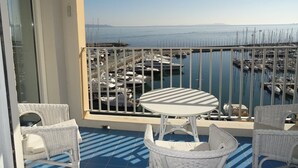 A balcony with a view of a marina, white wicker furniture, and a pool. - Hyères Port T2 with Air Conditioning and Wifi, Sea View (Hyères)