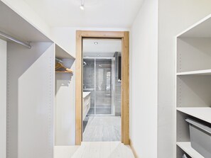 A narrow hallway leading to a bathroom with a glass shower enclosure.