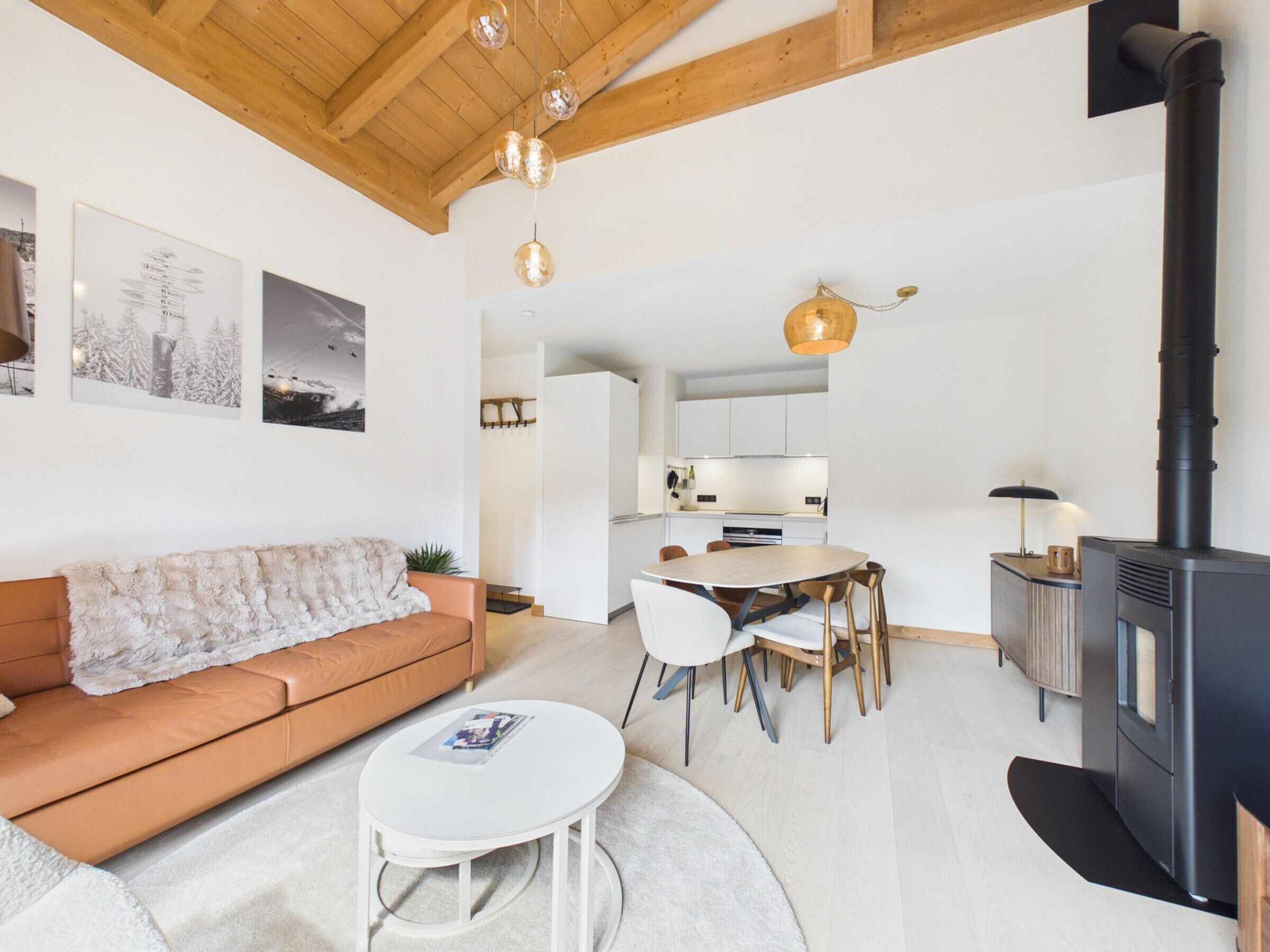 Una sala moderna con un sofá, una mesa redonda y una zona de cocina con estufa.