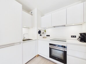 A modern kitchen with white cabinetry, stainless steel appliances, and a built-in oven.
