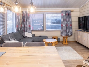 A modern living room with a sofa, coffee table, and TV. - Talvitupa by Interhome (Kuusamo)