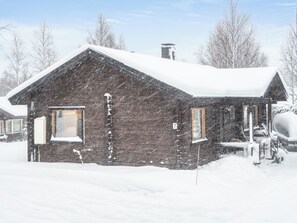 A wooden cabin with a snow-covered roof, a chimney, and a number '7' on the side.